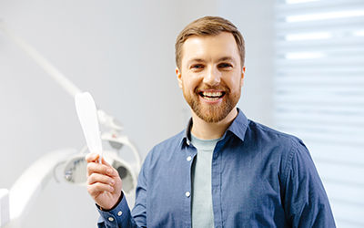 Happy dentist casually smiling in his office